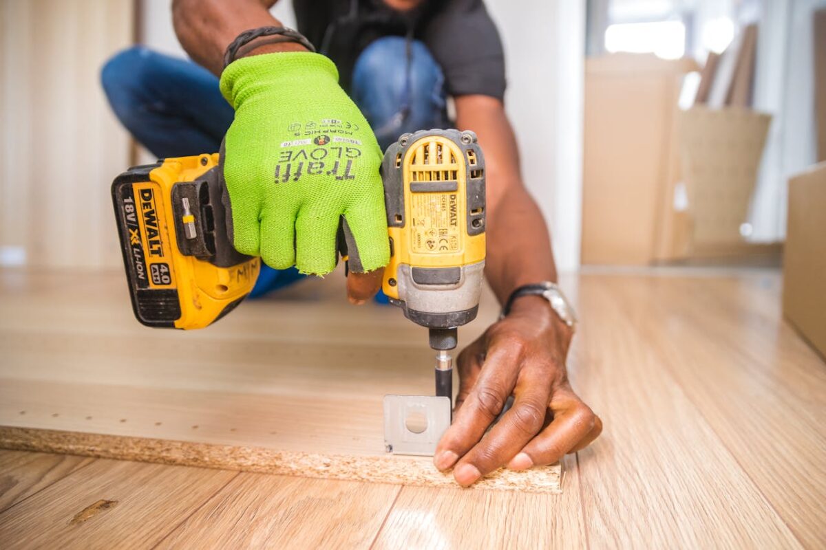 services-03 Man using a power drill for home improvement on a wooden floor with precision.
